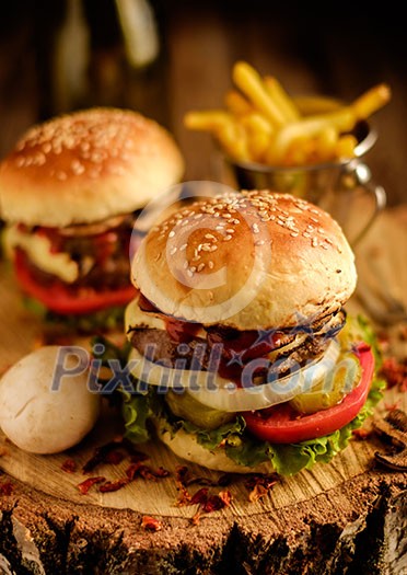 Delicious homemade hamburger with lettuce and cheese. Fried chips and burger on wooden background. Shallow depth of field. Delicious homemade hamburger with lettuce and cheese. Fried chips and burger on wooden background. Shallow depth of field.