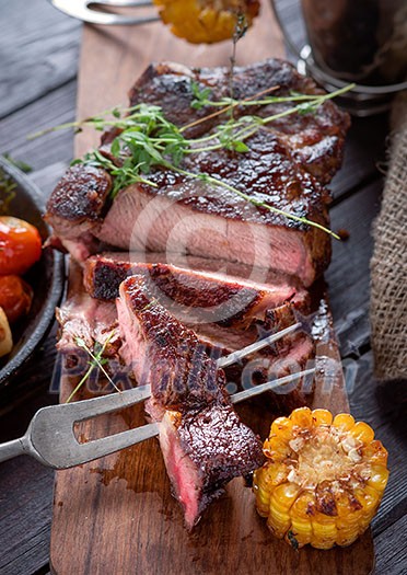 Grilled steak sliced on a cutting board. Entrecote with vegetables on a wooden background. Grilled steak sliced on a cutting board. Entrecote with vegetables on a wooden background.