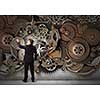 Young businessman fixing gears mechanism with wrench