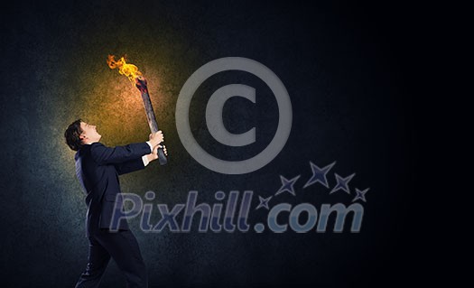 Young businessman holding burning torch in hand Young businessman holding burning torch in hand