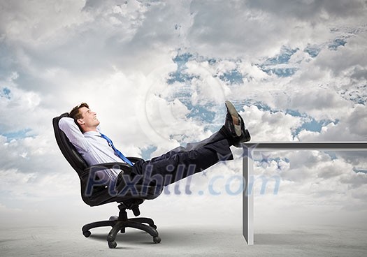 Smiling businessman sitting in chair with legs on table Smiling businessman sitting in chair with legs on table