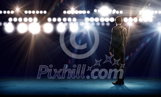 Rear view of businessman standing in lights of stage Rear view of businessman standing in lights of stage