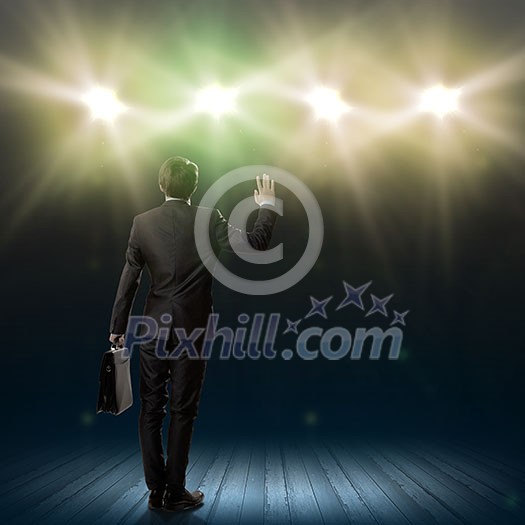 Rear view of businessman standing in lights of stage Rear view of businessman standing in lights of stage