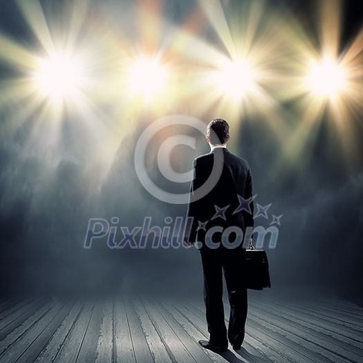 Rear view of businessman standing in lights of stage Rear view of businessman standing in lights of stage