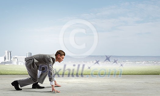 Side view of young businessman in start position ready to run Side view of young businessman in start position ready to run