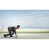 Side view of young businessman in start position ready to run