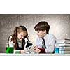 Cute girl and boy at chemistry lesson making tests