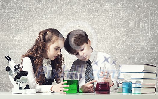 Cute girl and boy at chemistry lesson making tests Cute girl and boy at chemistry lesson making tests