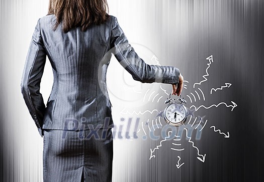 Rear view of businesswoman holding old alarm clock Rear view of businesswoman holding old alarm clock