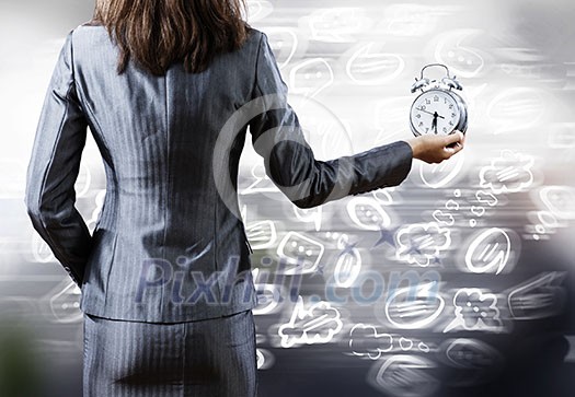 Rear view of businesswoman holding old alarm clock Rear view of businesswoman holding old alarm clock