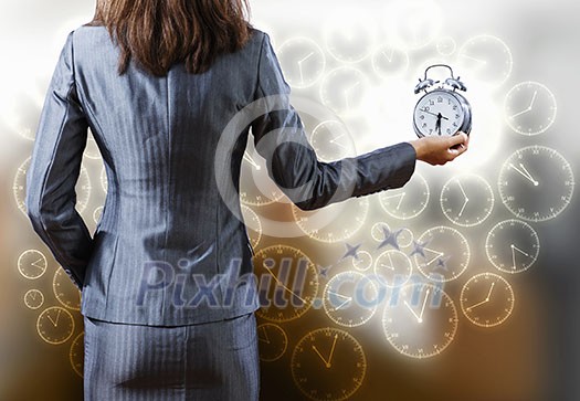 Rear view of businesswoman holding old alarm clock Rear view of businesswoman holding old alarm clock