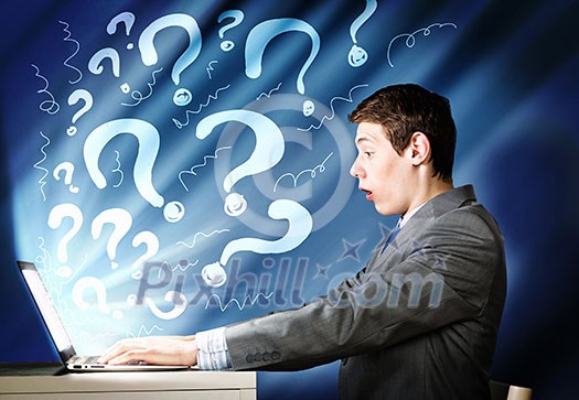 Young businessman looking shocked into laptop monitor Young businessman looking shocked into laptop monitor