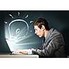 Young businessman looking shocked into laptop monitor