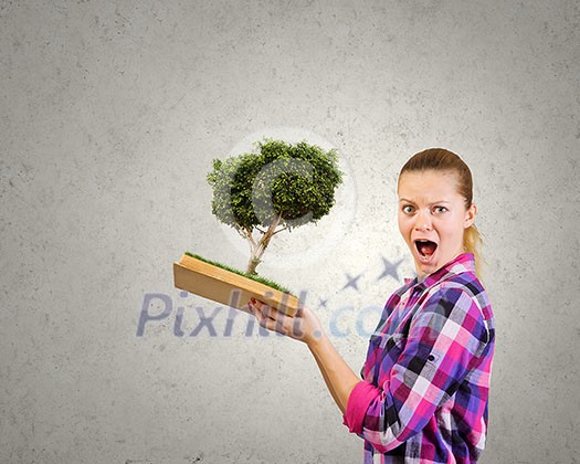 Young woman in casual holding opened book with green tree Young woman in casual holding opened book with green tree