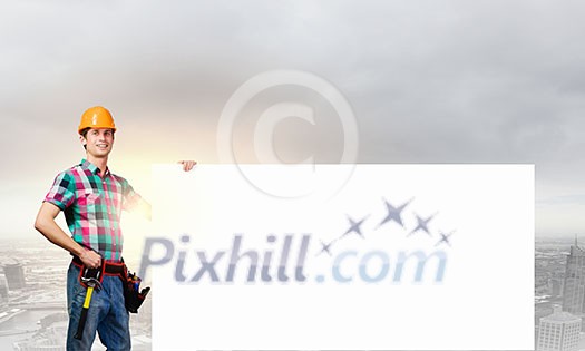 Young repairman holding white blank banner. Place for text Young repairman holding white blank banner. Place for text