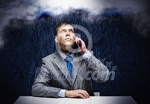 Young frustrated businessman under rain talking on mobile phone Young frustrated businessman under rain talking on mobile phone