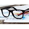 Eye glasses lying on papers with graphs and diagrams