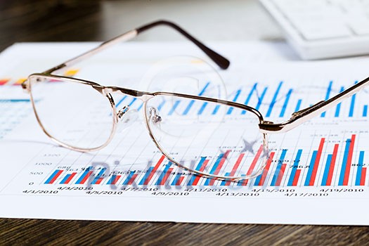 Eye glasses lying on papers with graphs and diagrams