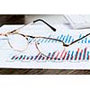 Eye glasses lying on papers with graphs and diagrams