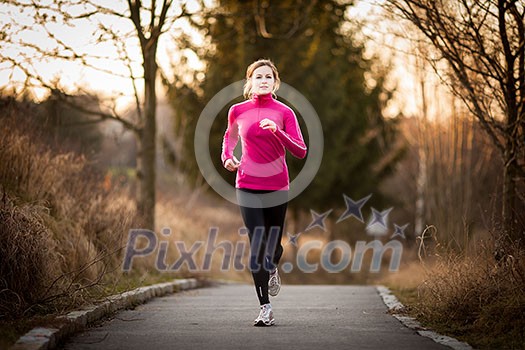 Young woman running outdoors in a city park on a cold fall/winter day Young woman running outdoors in a city park on a cold fall/winter day