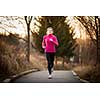Young woman running outdoors in a city park on a cold fall/winter day