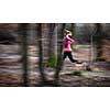 Young woman running outdoors in a city park on a cold fall/winter day (motion blurred image)