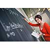 Pretty, young college student writing on the chalkboard/blackboard during a math class (color toned image)