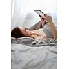 Young woman using her tablet computer in her bed (color toned image; shallow DOF)