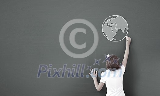 Cute little girl standing with back and drawing planet on blackboard Cute little girl standing with back and drawing planet on blackboard