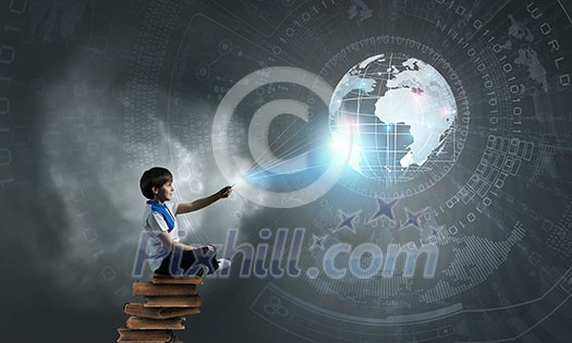 Cute school boy sitting on pile of books and using his smartphone Cute school boy sitting on pile of books and using his smartphone