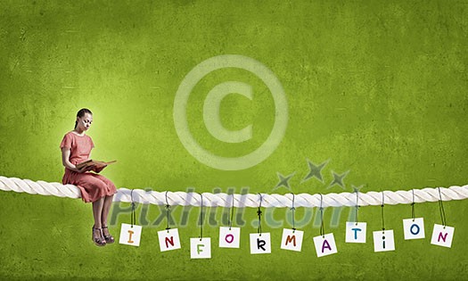 Young woman in red dress sitting on rope with book in hand Young woman in red dress sitting on rope with book in hand