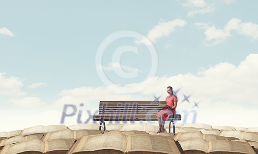 Young woman sitting on bench and reading book Young woman sitting on bench and reading book