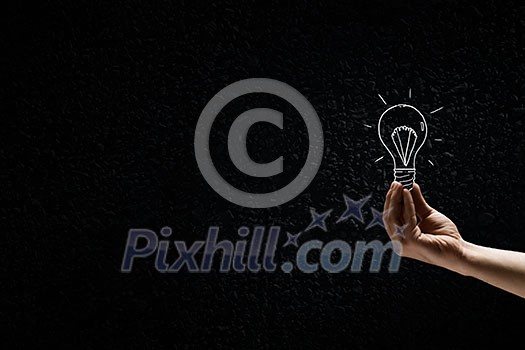Male hand on dark background showing drawn light bulb Male hand on dark background showing drawn light bulb