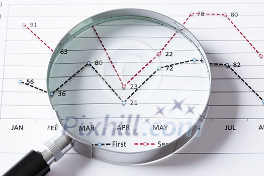 Magnifing glass and documents with analytics data lying on table Magnifing glass and documents with analytics data lying on table