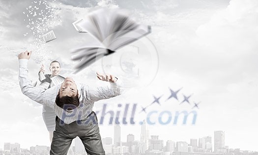 Young businessman trying to evade from thrown book Young businessman trying to evade from thrown book