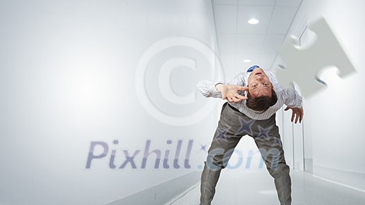 Businessman bent over and evading from flying puzzle element Businessman bent over and evading from flying puzzle element