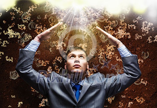 Businessman protecting head with arms from falling money symbols Businessman protecting head with arms from falling money symbols