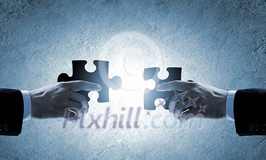 Close up image of hands connecting puzzle elements Close up image of hands connecting puzzle elements