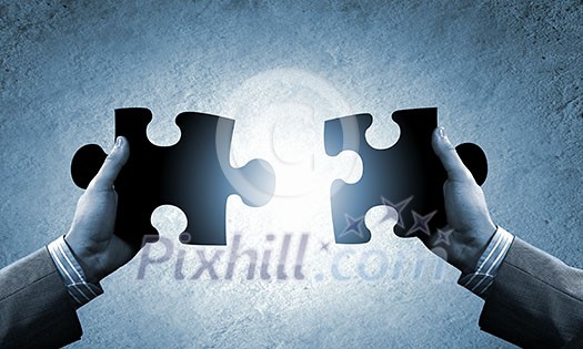 Close up image of hands connecting puzzle elements Close up image of hands connecting puzzle elements