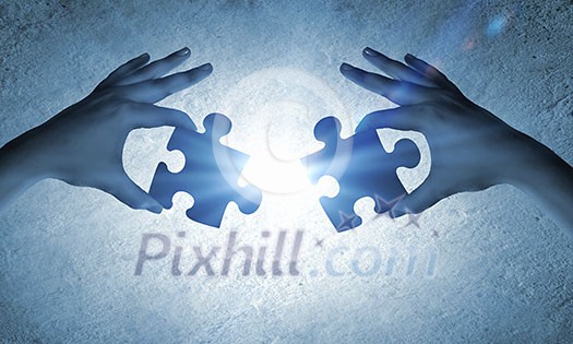 Close up image of hands connecting puzzle elements Close up image of hands connecting puzzle elements