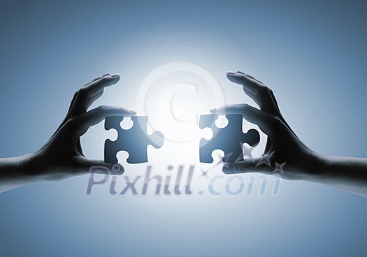 Close up image of hands connecting puzzle elements Close up image of hands connecting puzzle elements