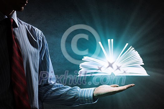 Close up of hand holding in palm glowing book Close up of hand holding in palm glowing book