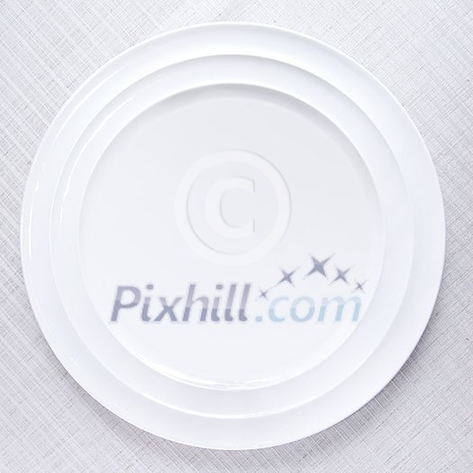 Empty white plate on tablecloth Empty white plate on tablecloth