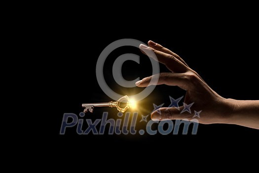 Close up image of business person holding shining key Close up image of business person holding shining key