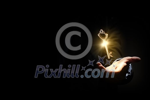 Close up image of business person holding shining key Close up image of business person holding shining key