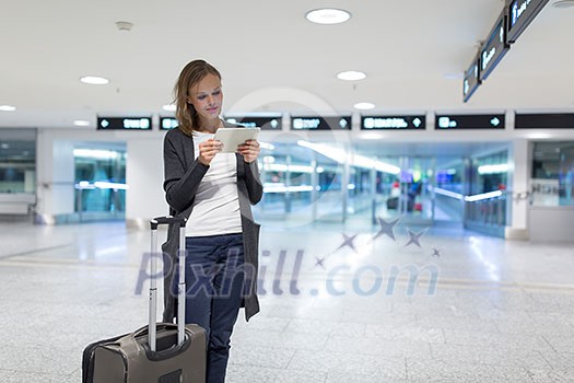 Young female passenger at the airport, using her tablet computer while waiting for her flight (color toned image) Young female passenger at the airport, using her tablet computer while waiting for her flight (color toned image)
