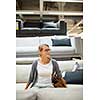 Pretty, young woman choosing the right furniture for her apartment in a modern home furnishings store (color toned image; shallow DOF)