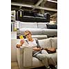 Pretty, young woman choosing the right furniture for her apartment in a modern home furnishings store (color toned image; shallow DOF)