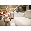 Pretty, young woman choosing the right furniture for her apartment in a modern home furnishings store (color toned image; shallow DOF)