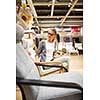 Pretty, young woman choosing the right furniture for her apartment in a modern home furnishings store (color toned image; shallow DOF)